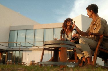 Young couple sharing a bottle of wine during sunset outside Finca de los Arandinos hotel, Entrena, Spain.