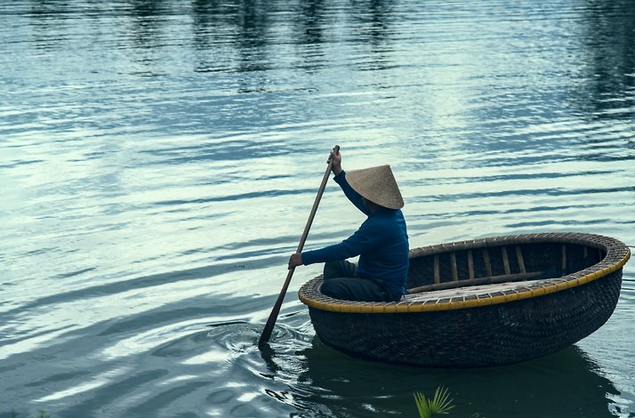 Traditional basket boat with a person rowing on calm water