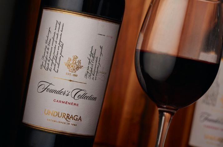 A rich red wine bottle and glass, highlighting its label and deep color