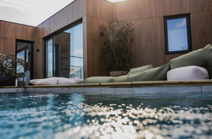 Outdoor seating area by a sparkling pool, surrounded by greenery