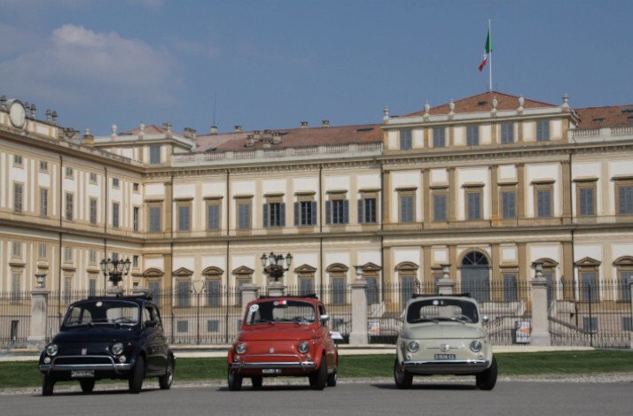 Three Fiat 500s are parked in front of the Royal Villa of Monza building.