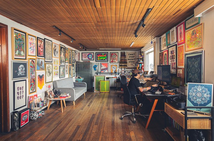 Creative workspace with framed art, wooden floors, and an artist working at a desk