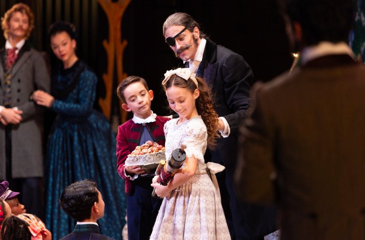 Clara receives the Nutcracker from Drosselmeyer at a festive holiday party.