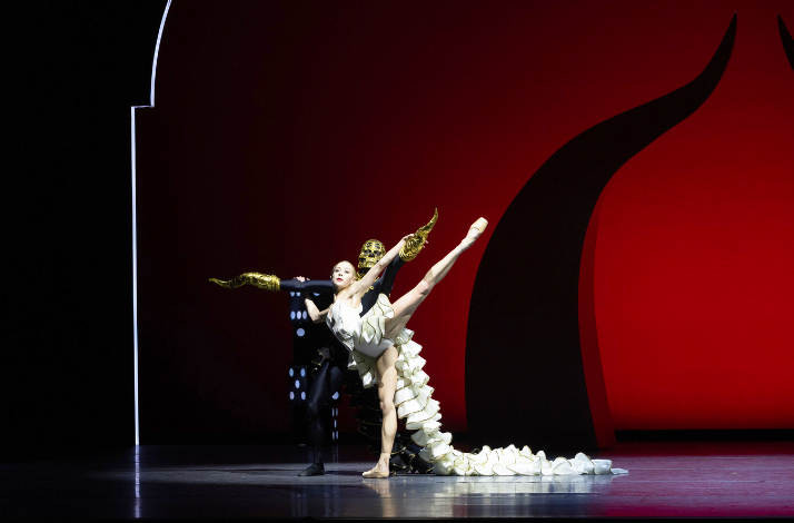 Duet with dancer in white, dramatic pose, gold gloves, bold red and black set.
