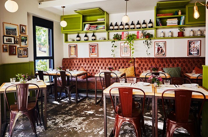 A brightly lit interior of La Alacena Trattoria's restaurant, showcasing a variety of tables and chairs