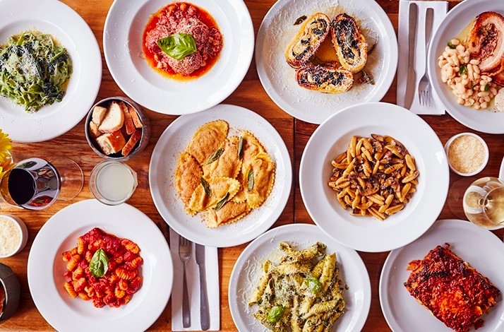 A high-angle view of various Italian dishes arranged on a wooden table, served at La Alacena Trattoria restaurant