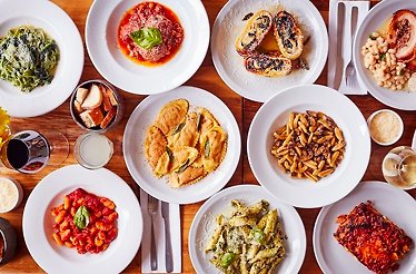 A high-angle view of various Italian dishes arranged on a wooden table, served at La Alacena Trattoria restaurant