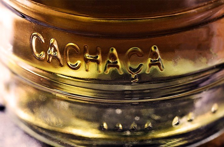 The word CACHAÇA is embossed on a bottle.