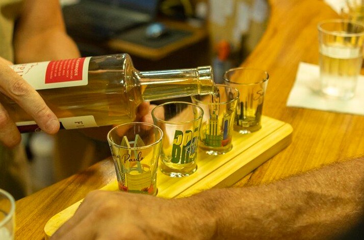 Pindorama cachaça fills shot glasses on a wooden tray.