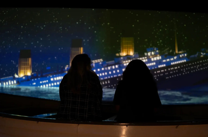 Two people with their backs to the camera exploring Titanic: An Immersive Voyage.