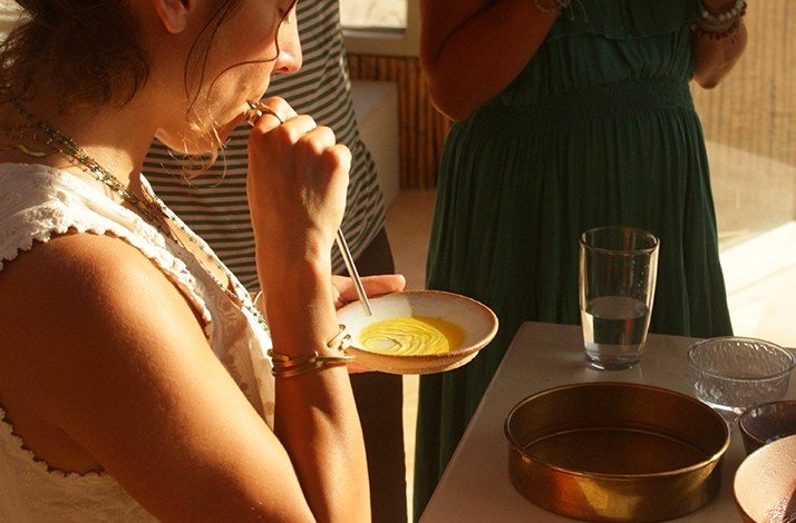 A person blowing air into a bowl with natural pigments to create art in a guided class by artist Fabiana Burr.