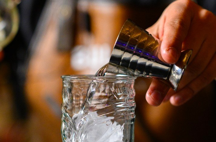 Two hands are raising glasses of drinks in a toast.