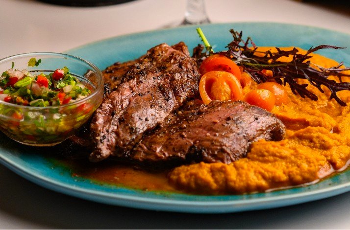 Close-up of a hand holding a glass of a light-colored drink garnished with lime slices and ice.