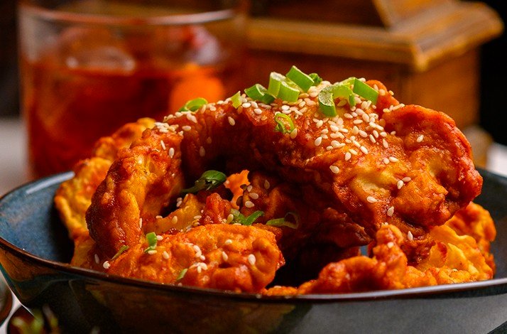 Crispy, spicy coated chicken topped with sesame seeds and green onions