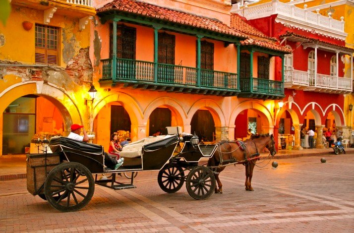 A horse-drawn carriage moving through a Colombian street.