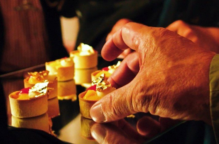 A person picking a small serving of a gourmet meal out of a tray.