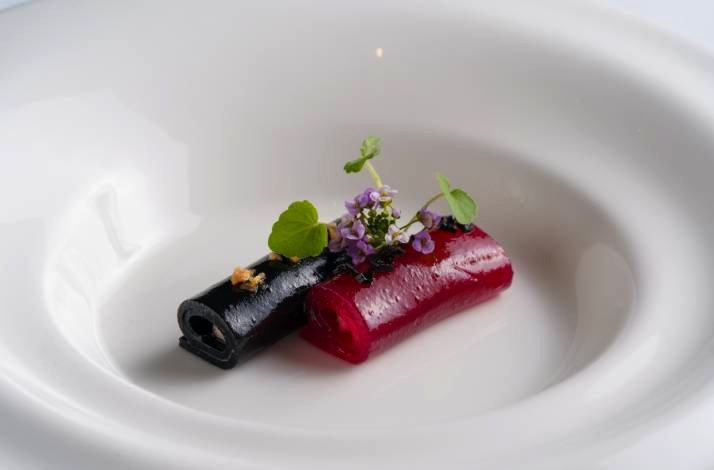 Two rolled sheets, one black and one red, topped with edible flowers.