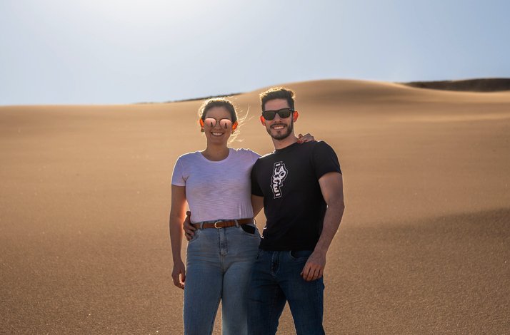 A couple wearing sunglasses posing for a photo in Salt Mountain Range, San Pedro de Atacama, Chile.