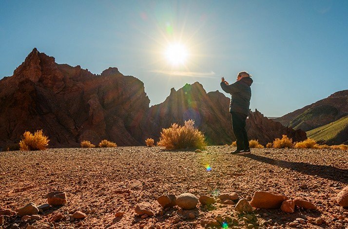 A person taking a photo of a rock formation.