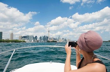 A girl takes a photo of Toronto from the Harbour Cruise.
