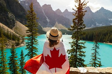 Girl in a hat and with a Canadian flag on her shoulders against the backdrop of Moraine Lake.