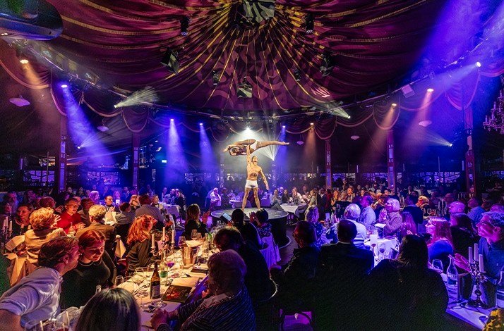 A man on stage holding a woman overhead with one arm at Teatro Munich.