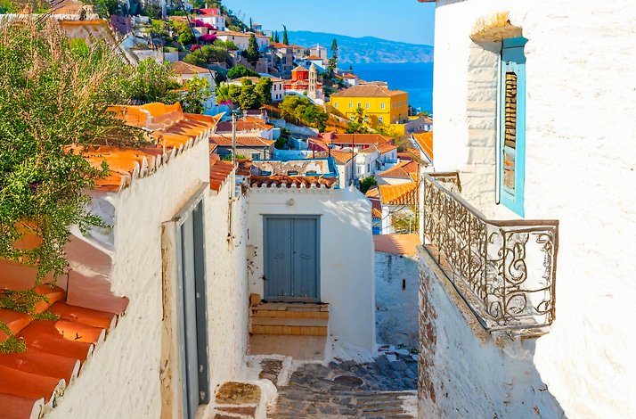 A picturesque view of a narrow alleyway in a Greek village at Hydra Island, showcasing buildings and a vibrant atmosphere