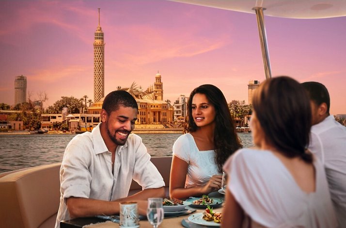 A group of people enjoying dinner while sailing the Nile on a private yacht.
