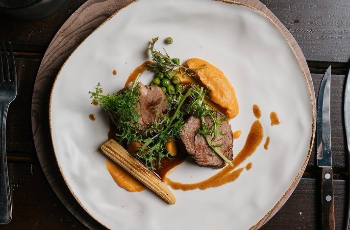 Top view of a fine gourmet plated dish, two cuts of beef, with vegetables