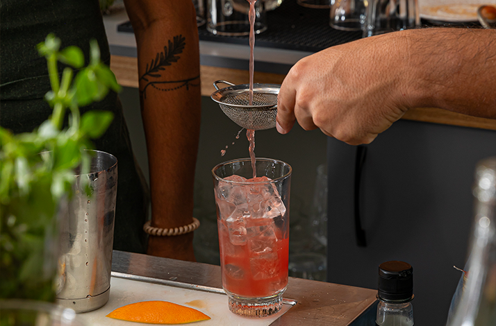 The process of pouring a cocktail through a sieve.
