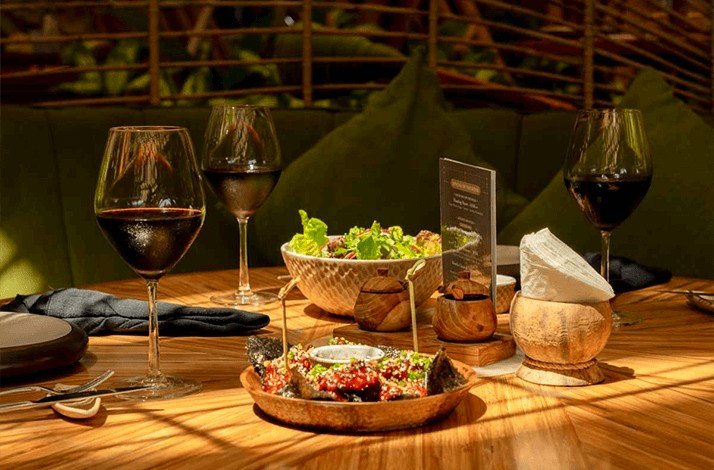 Dining table at Luna Beach Club with red wine, salad, and appetizers in a cozy setting.