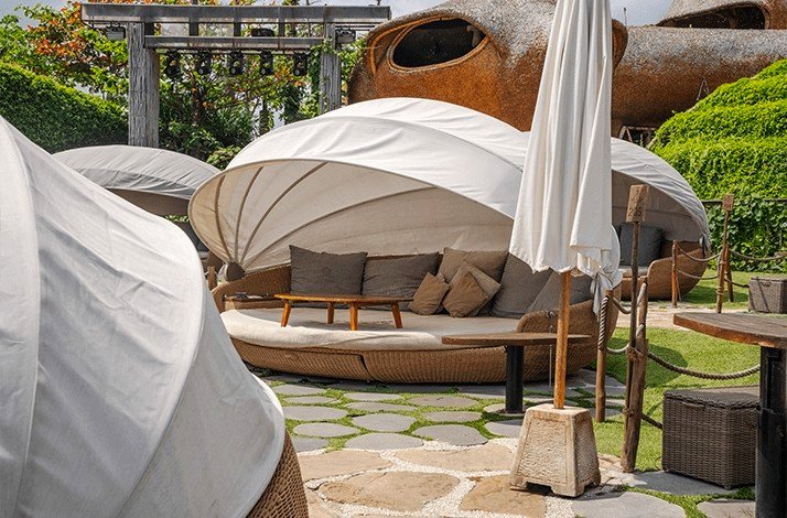 A comfortable daybed with pillows under a covering in the beach of Luna Beach Club.