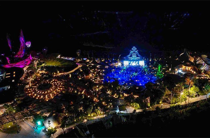 Night view of Luna Beach Club, Bali, illuminated with vibrant lights and colorful displays.