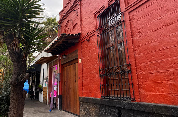 Exterior of a red building in Coyoacán, Mexico City, featuring wooden and iron detailing.