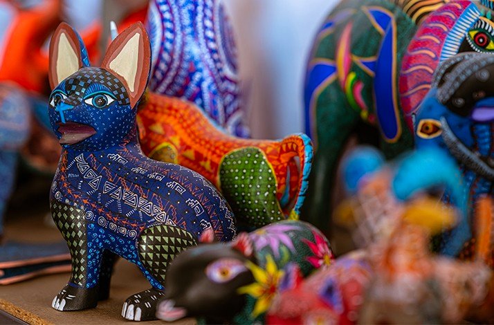 A display of several colorful, hand-painted animal figurines, with a blue and white patterned creature in the foreground.