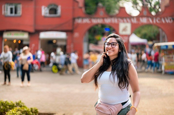 A girl smiling brightly while standing on a colorful street in Mexico.