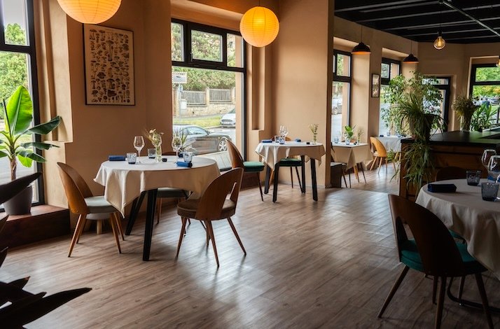 Cozy dining area with natural light, warm tones, and minimalist table settings at Leaf Restaurant