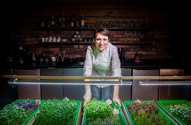 Chef Bára Šimůnková with fresh microgreens inside LEAF restaurant.
