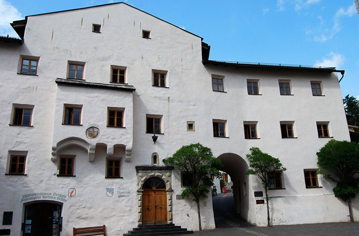 White historic building with wooden windows, arched passageway, and main wooden door