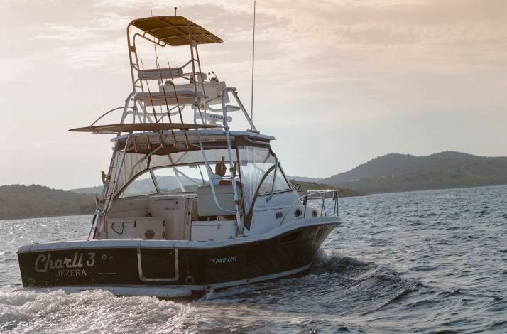Motorboat cruising on the sea at sunset with low hills in the background.