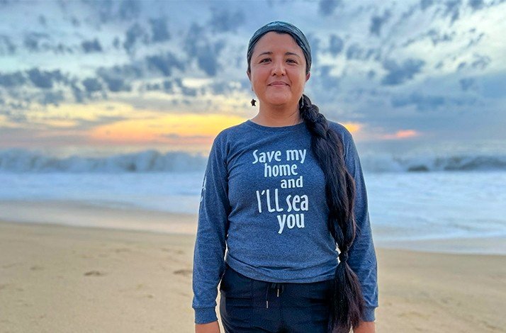 A woman posing for the photo on the shore during sunset