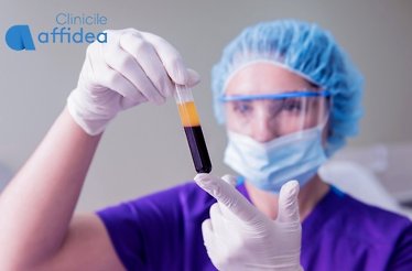 A medical professional examines a test tube of blood.
