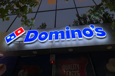 Domino's pizza neon sign on a building's facade.