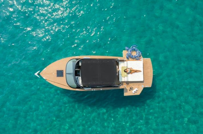 High-angle view of a woman relaxing on a boat deck in turquoise water at Dubrovnik. 