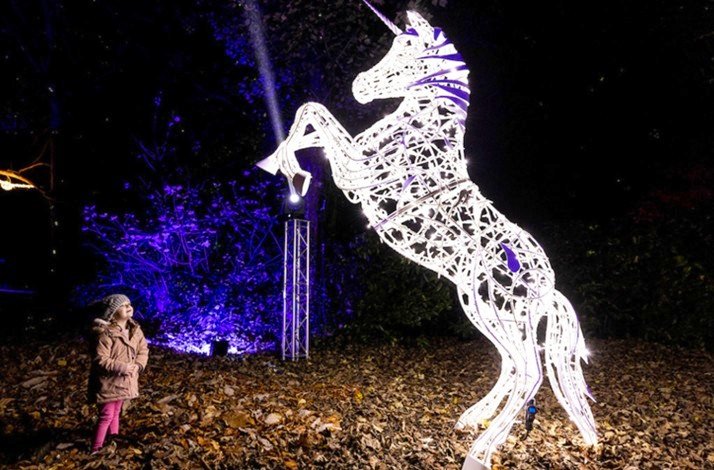 A giant unicorn created with numerous lights and lit at night.