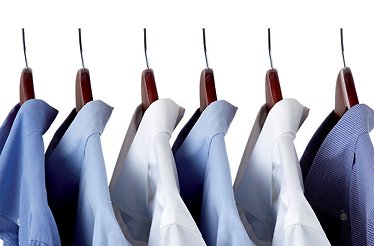 Neatly pressed shirts in blue and white, hung on wooden hangers