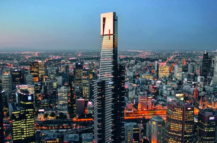Eureka Tower rising above Melbourne's illuminated skyline at dusk, with city lights stretching to the horizon.