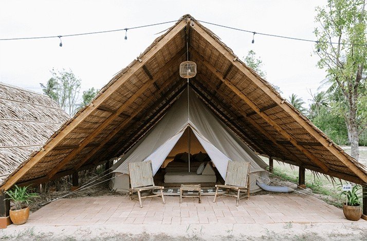 Entrance view of the Wonderfruit's boutique camping tents, along with some chairs and plants.