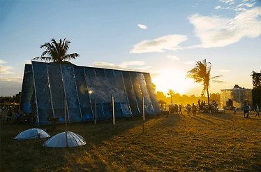 A sunset scene featuring a tent and several people standing nearby at the Wonderfruit festival.