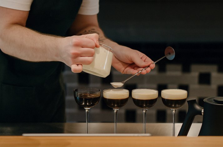A barista pouring steammed milk on coffee